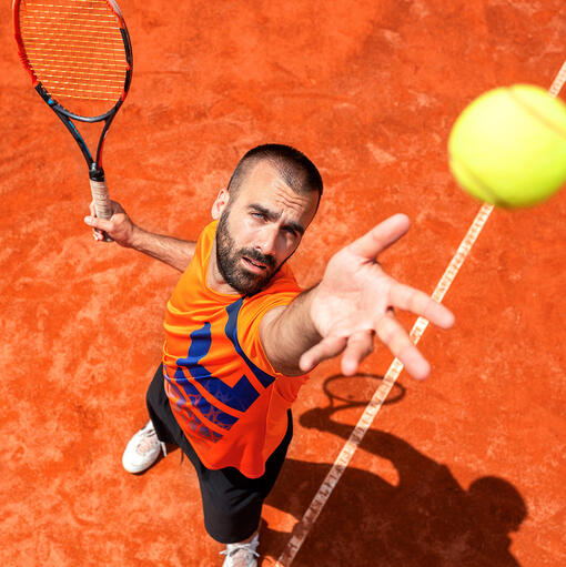 man die met de opslag bezig is, de service van het tennisspel gravel tennisbaan met man die de service slaat van bovenaf gefotografeerd - de service, zoals spin service, wordt getraind in tennisles van Gerard Bastiaans in Venray