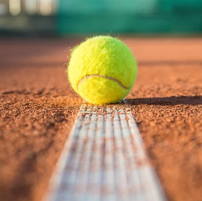 gravelbaan met gele tennisbal op de lijn sfeerbeeld van tennisbaan in Venray voor de site voor tennisles in Venray bij tennisclub Rodhe door trainer Gerard Bastiaans met KNLTB licentie